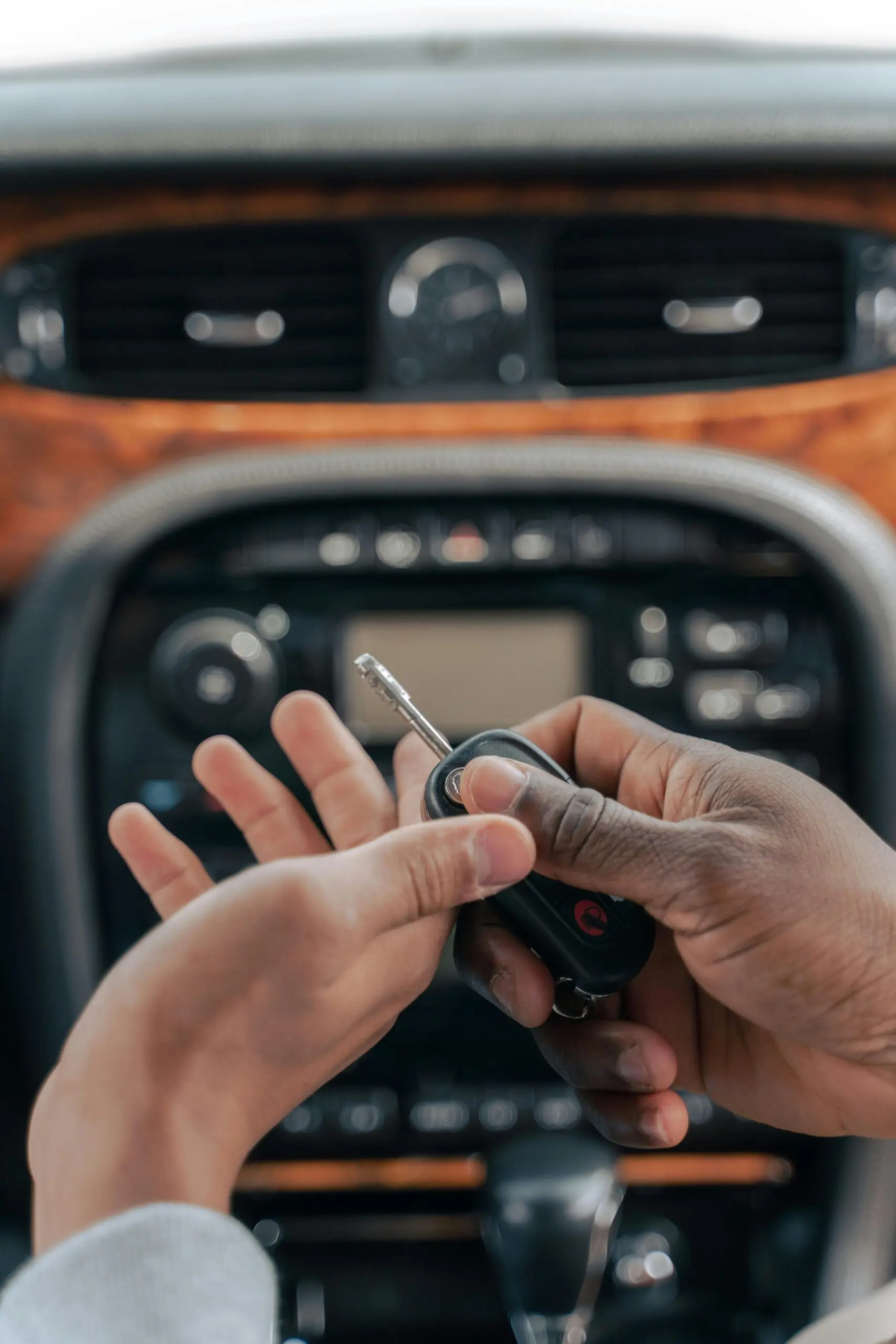 Hands exchanging a car key inside a vehicle, illustrating the concept of car ownership or a transfer of responsibility.